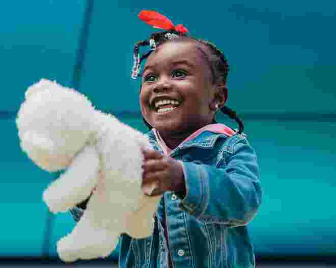 child holding a teddy bear and smiling
