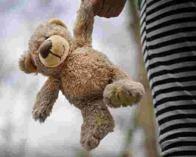 a teddy bear being carried by a child
